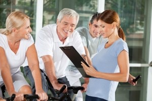 Fitnesstrainierin mit Senioren im Fitnesscenter erstellt Trainingsplan